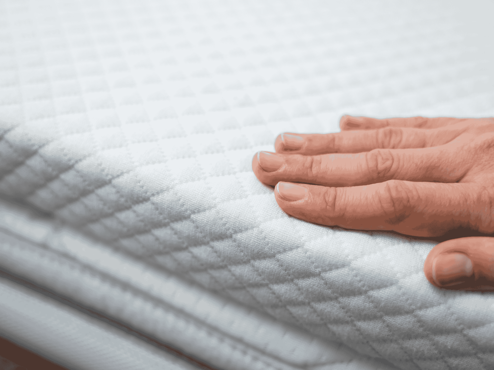 Hand checking the premium quilting of a full-size mattress for exceptional durability.