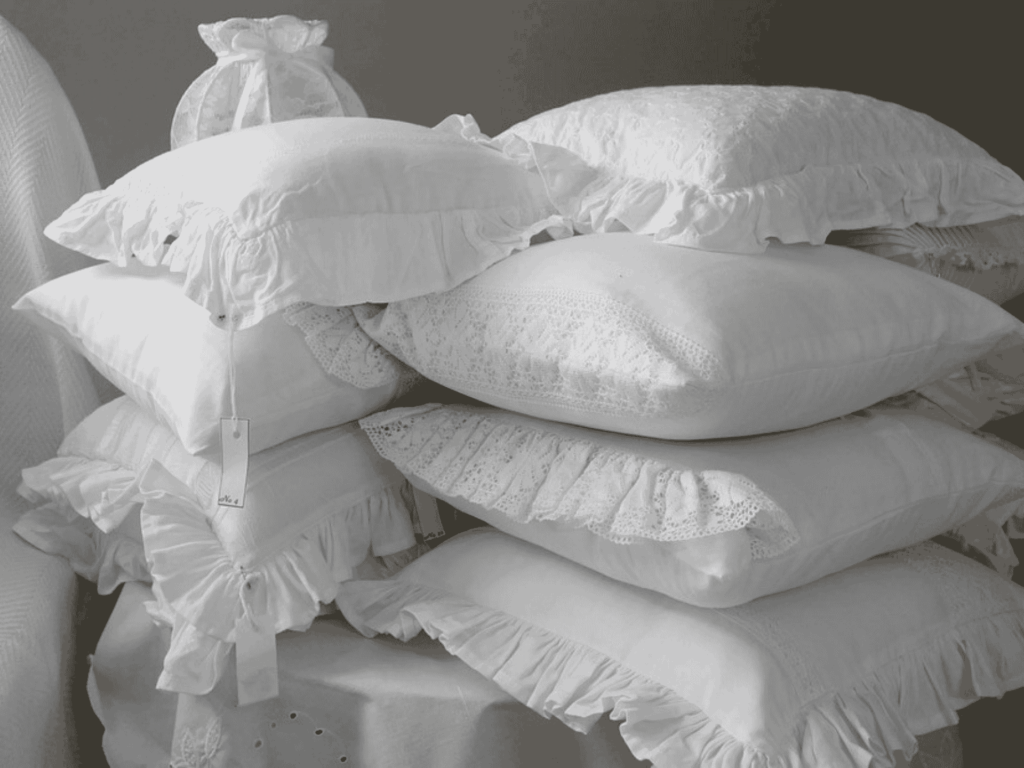 Stack of premium white pillows with delicate lace detailing for enhanced comfort and style.